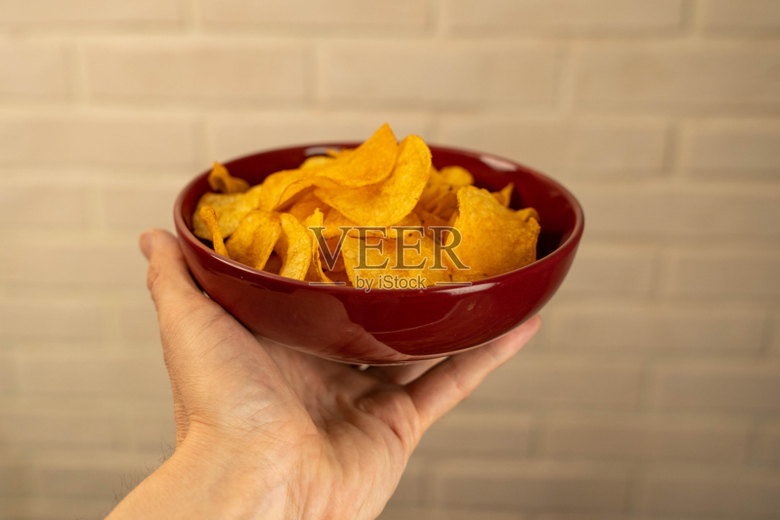 一只手拿着一个装满薯片的红碗照片摄影图片