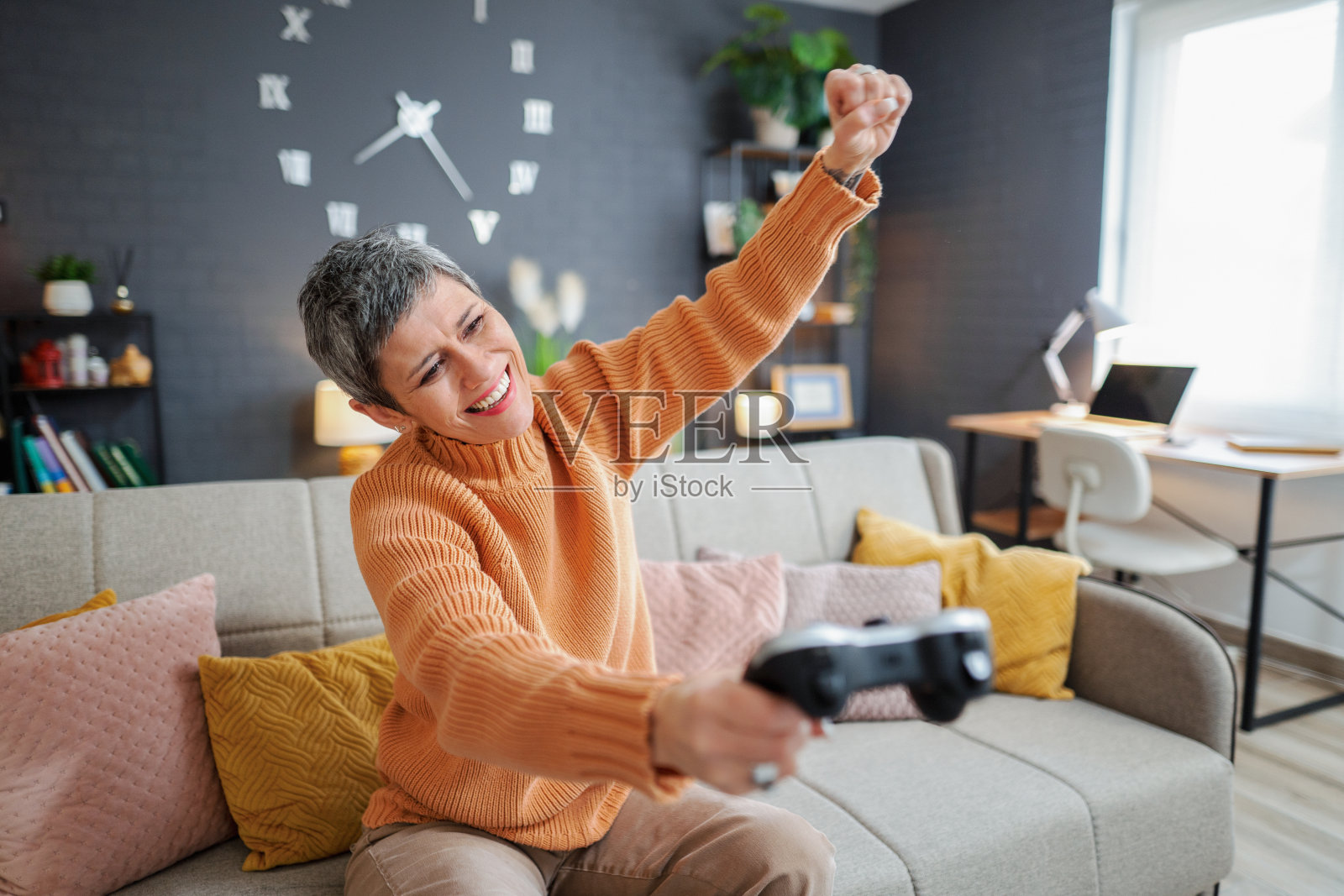 争强好胜、头发灰白的成熟的女人在客厅里玩电子游戏照片摄影图片