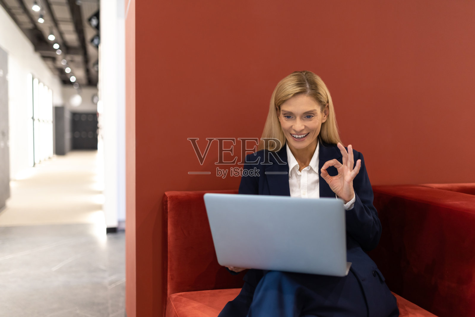 穿着西装在电脑前工作的女公司主管,露出ok的手势照片摄影图片