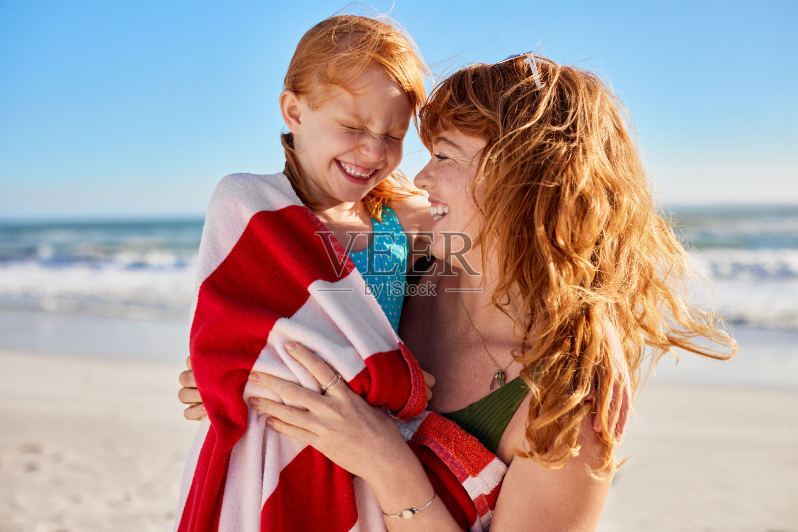 母亲和女儿在海里游泳后一起玩耍照片摄影图片