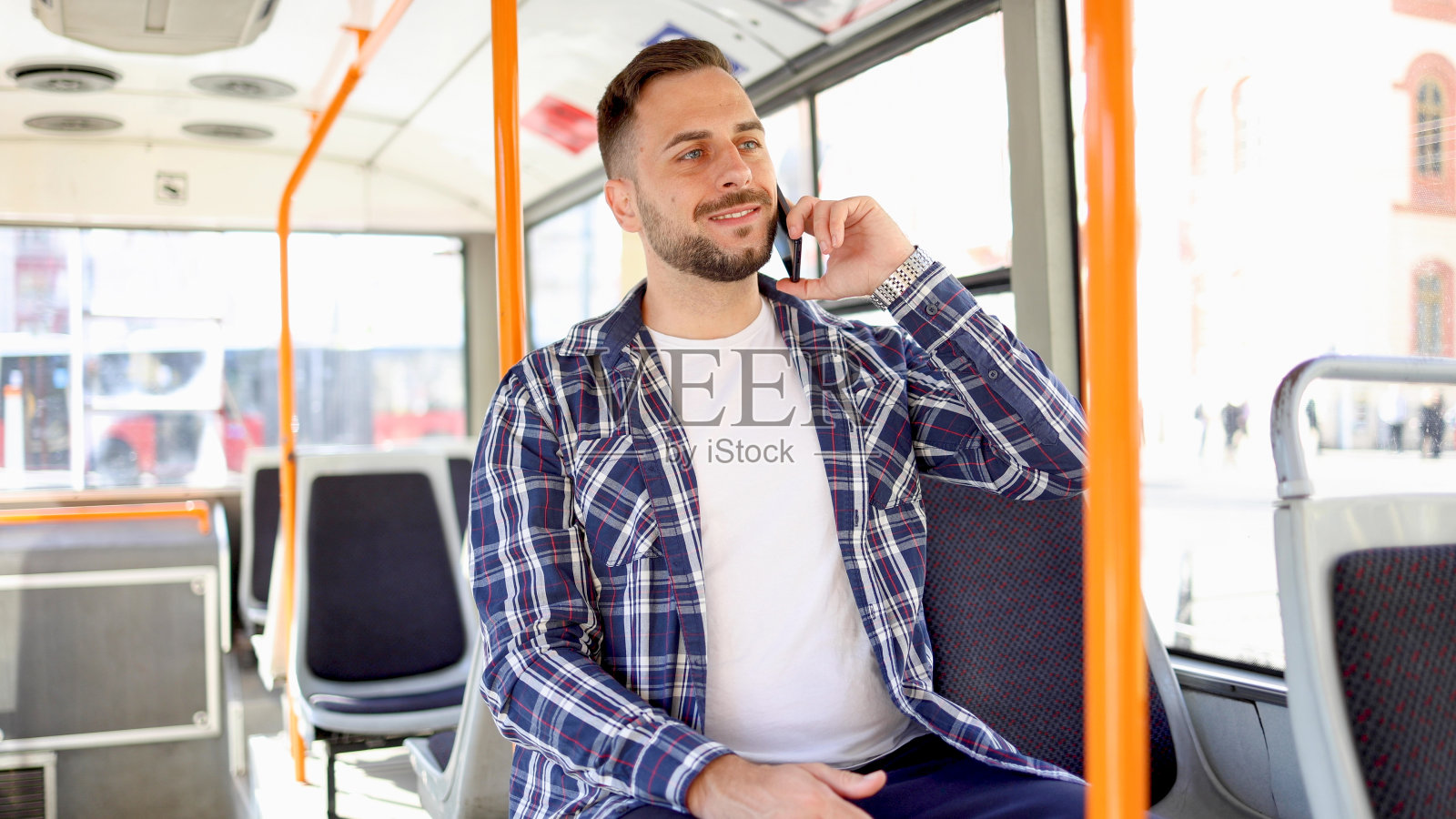 一个年轻人在公共汽车上用手机聊天照片摄影图片