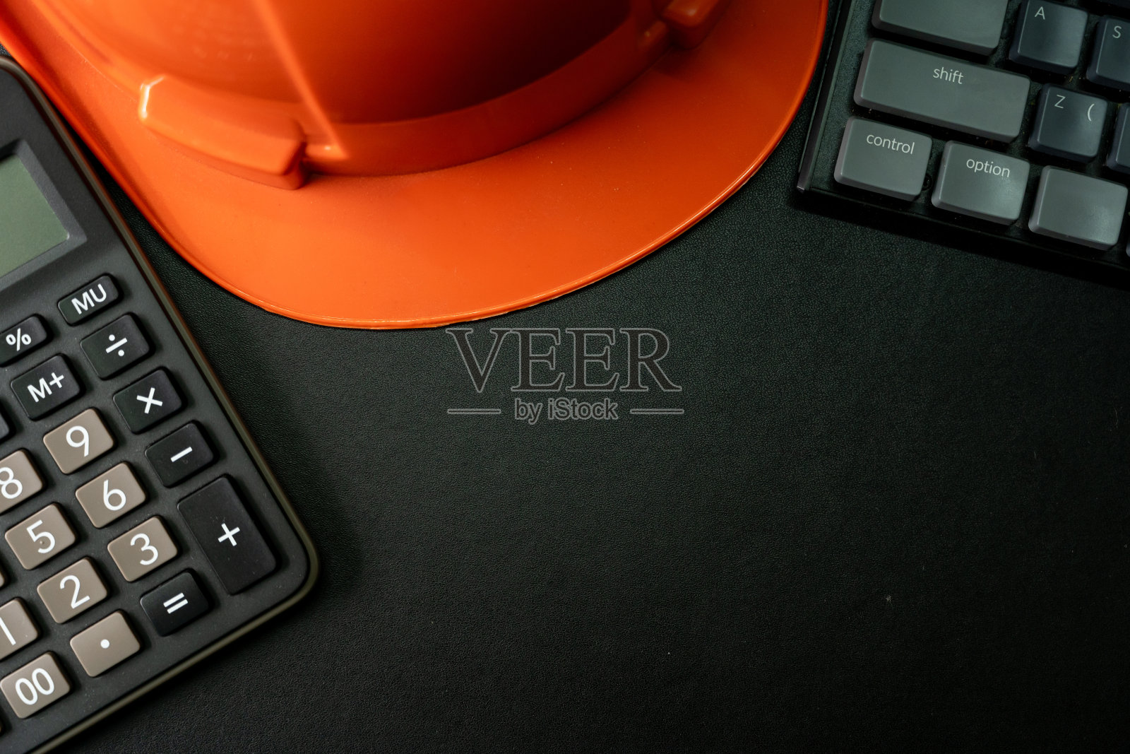 橙色安全帽或安全帽,键盘和计算器在黑色背景。商业建设理念或工程背景。带复制空间的俯视图。照片摄影图片