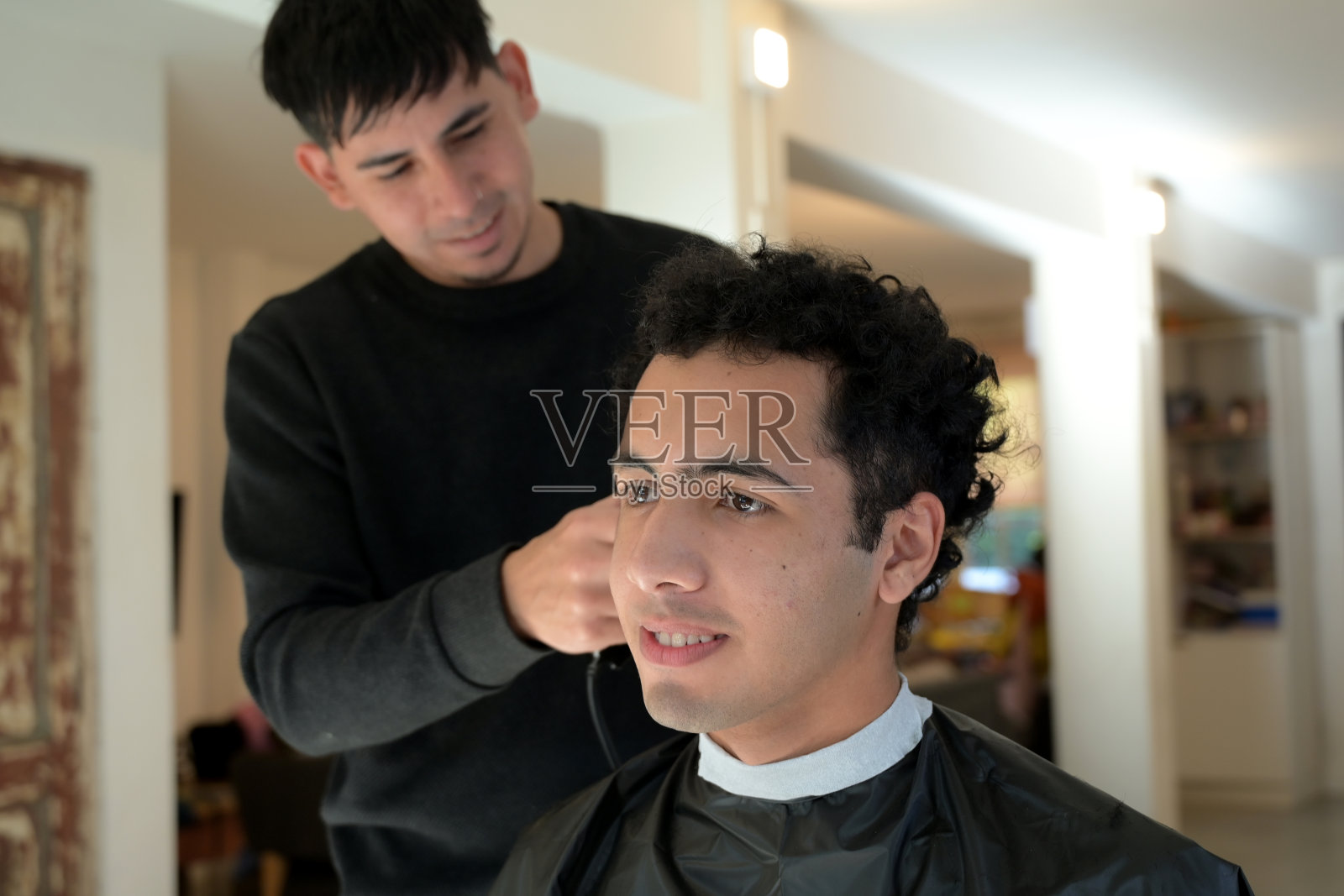 理发师正在给一个年轻的拉丁男子理发照片摄影图片
