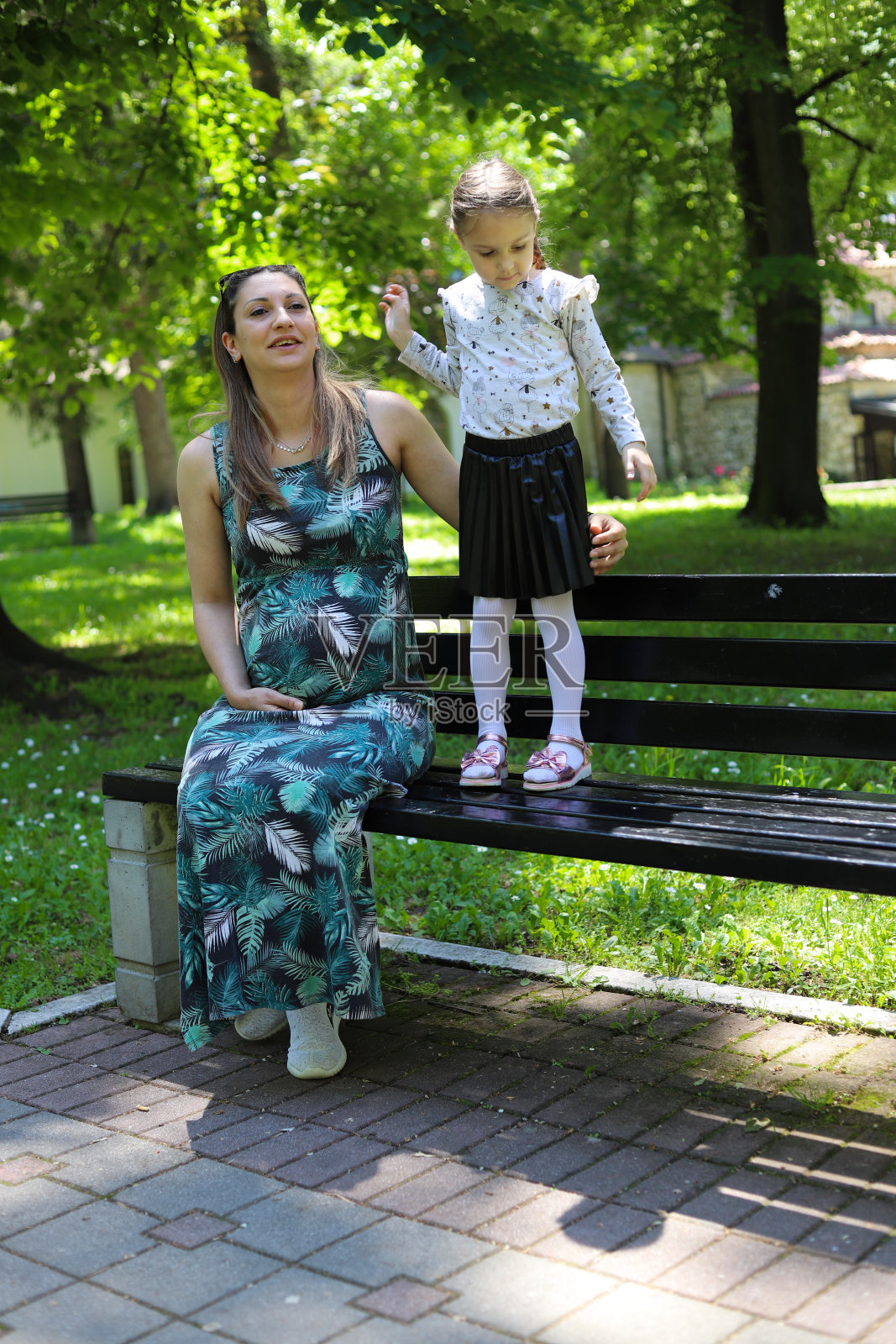 怀孕的妈妈和她的女儿带着一只小狗在镇上玩耍照片摄影图片