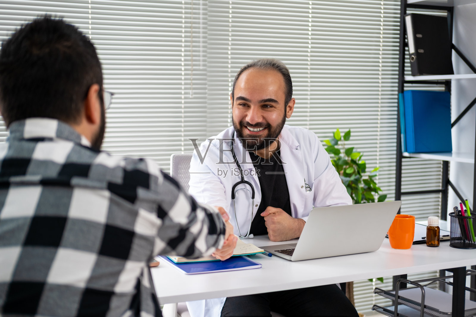 年轻的医生和他的病人握手照片摄影图片