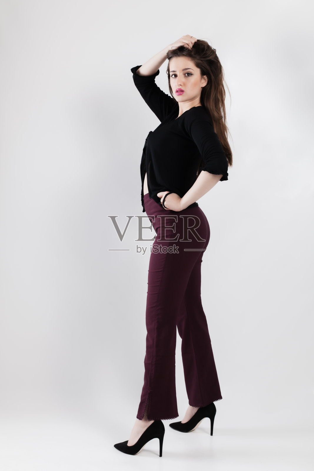 优雅的年轻女子在工作室里自信地摆姿势,穿着时髦的衣服照片摄影图片