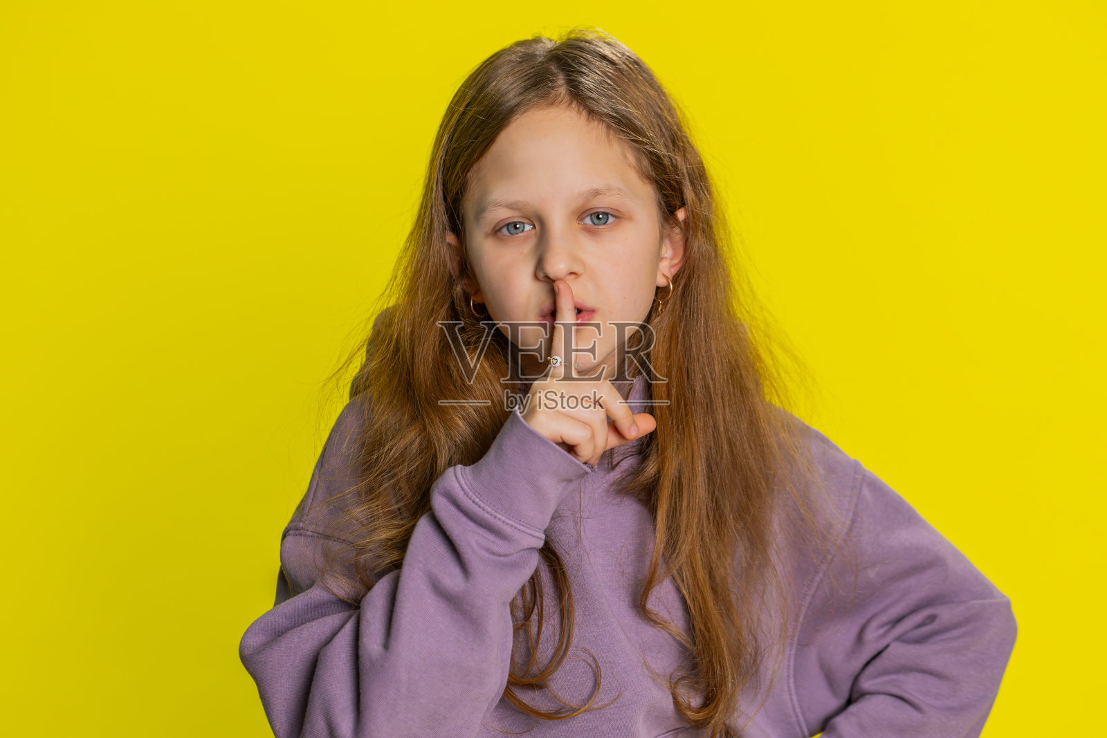青春期前的女孩把手指放在嘴唇上做沉默的手势,不讲八卦秘密,安静照片摄影图片