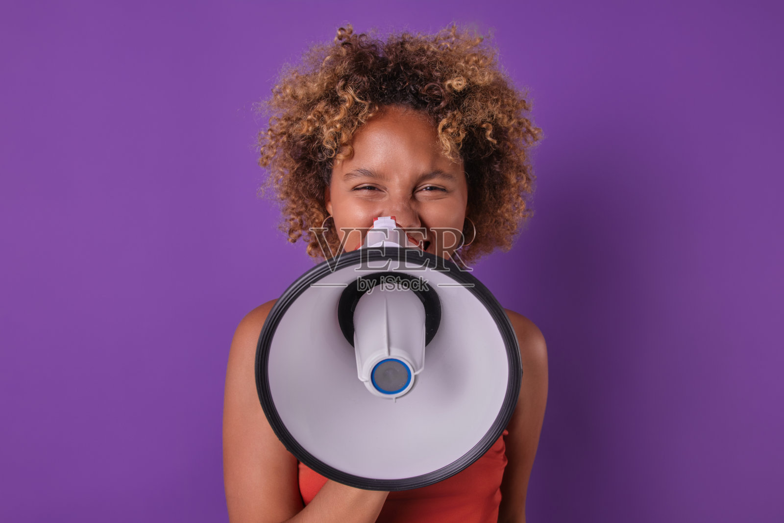 年轻的非裔美国妇女把扩音器靠近脸做狡猾的鬼脸照片摄影图片