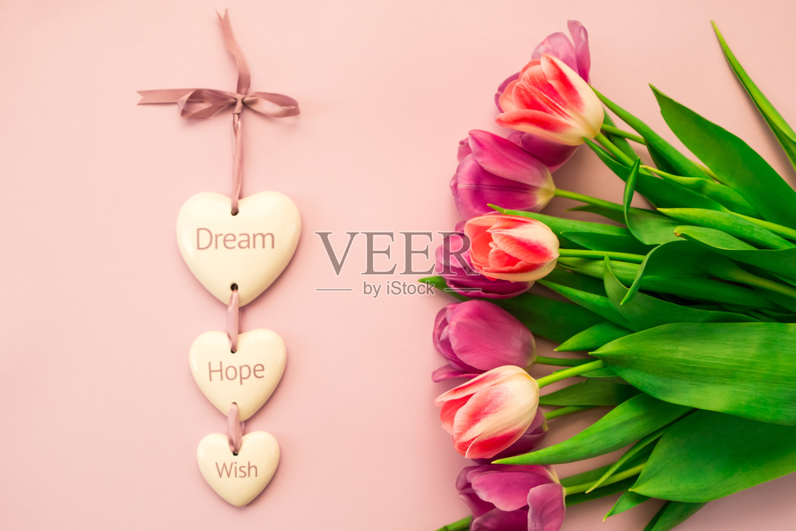 贺卡,横幅,粉红色背景上的粉红色和紫色郁金香和刻有“梦想,希望,愿望”字样的陶瓷心照片摄影图片