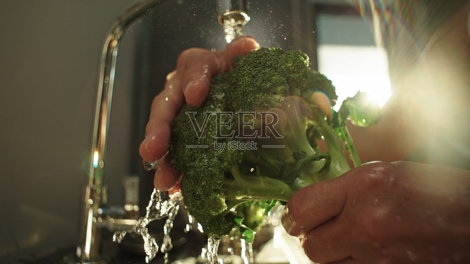 在厨房清洗西兰花蔬菜。照片摄影图片