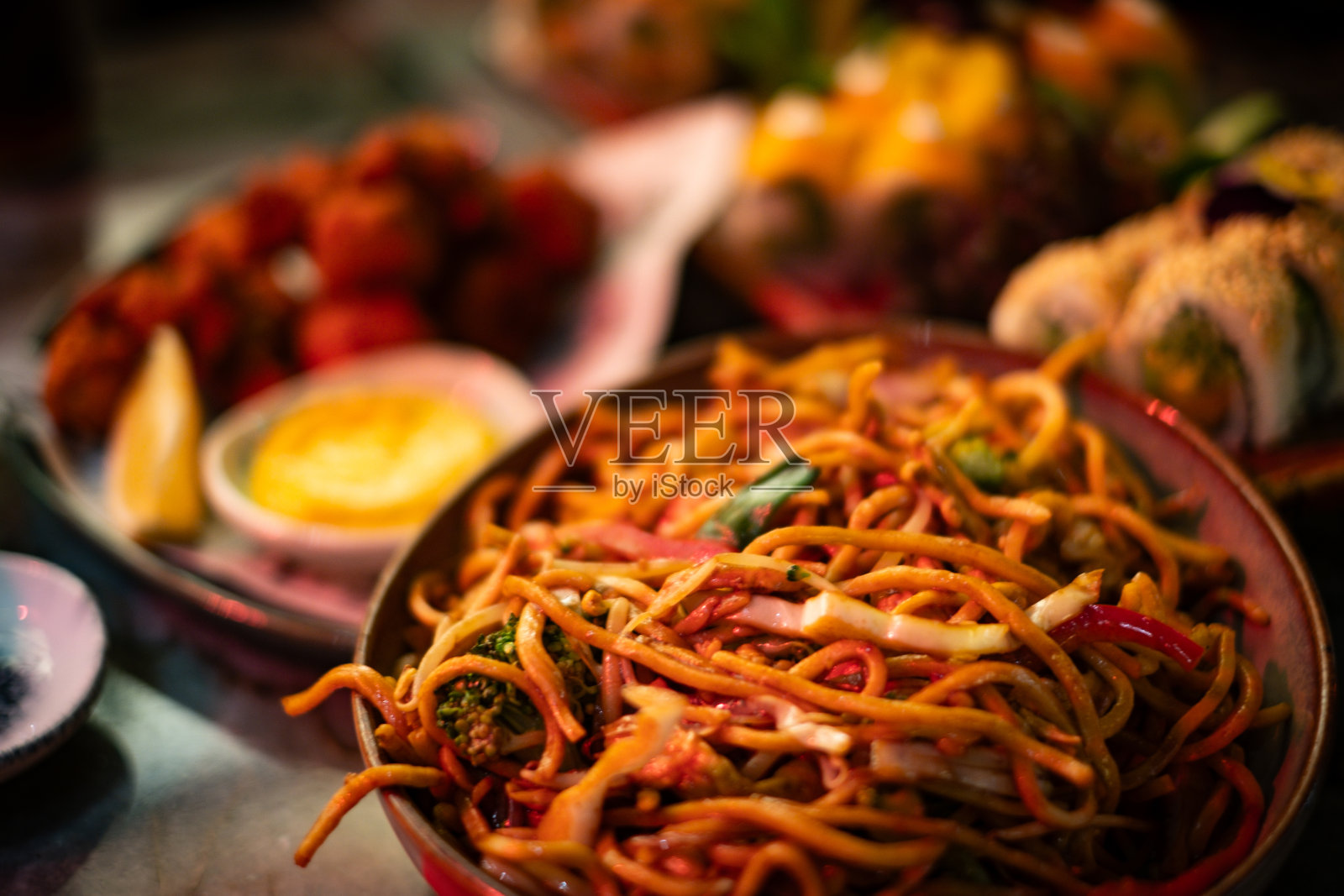 中国餐馆里桌子上的食物。桌子上有面条、寿司和脆皮鸡。照片摄影图片