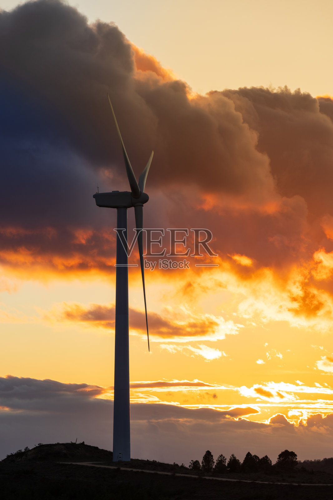 橙色和蓝色夕阳下的风力涡轮机。可再生可持续能源发电理念。照片摄影图片