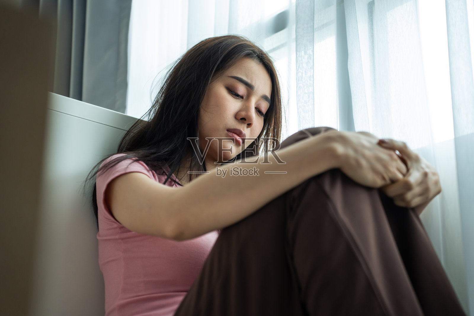 亚洲年轻沮丧的女人独自坐在家里的客厅里。迷人的不快乐的女性感到非常悲伤,孤独和沮丧的生活问题想到金钱债务,预算损失,破产照片摄影图片