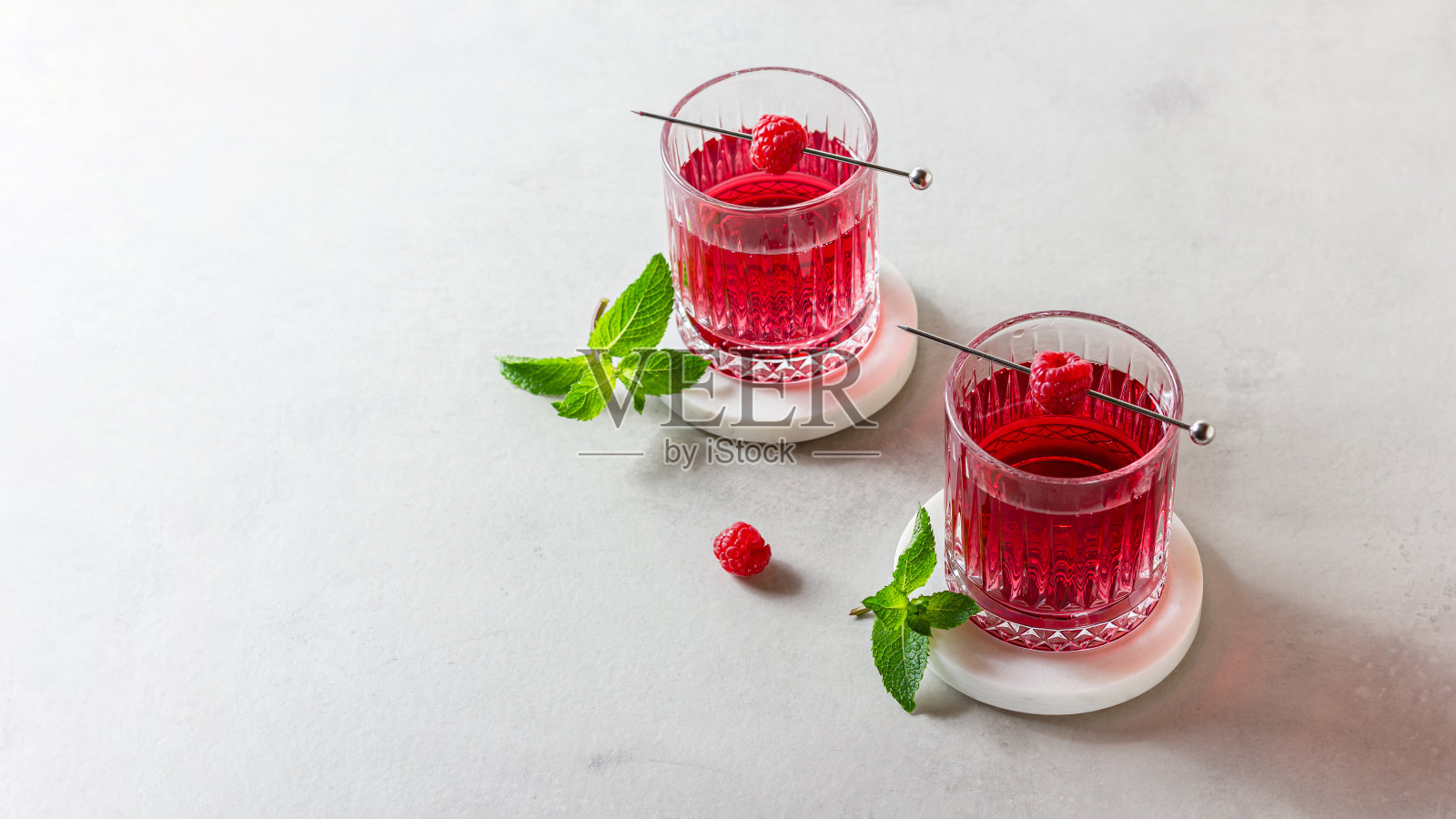 用玻璃杯盛着覆盆子鸡尾酒,放在大理石架子上照片摄影图片