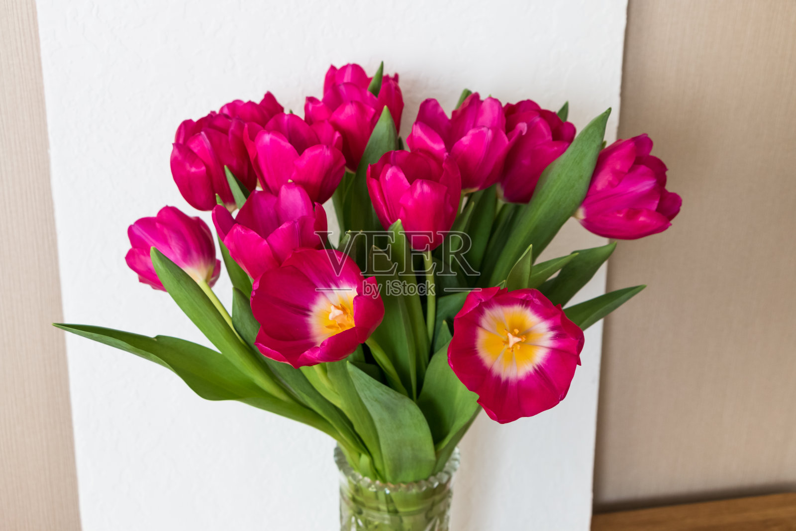 木桌上的玻璃花瓶里放着一束亮粉色的樱红色郁金香照片摄影图片