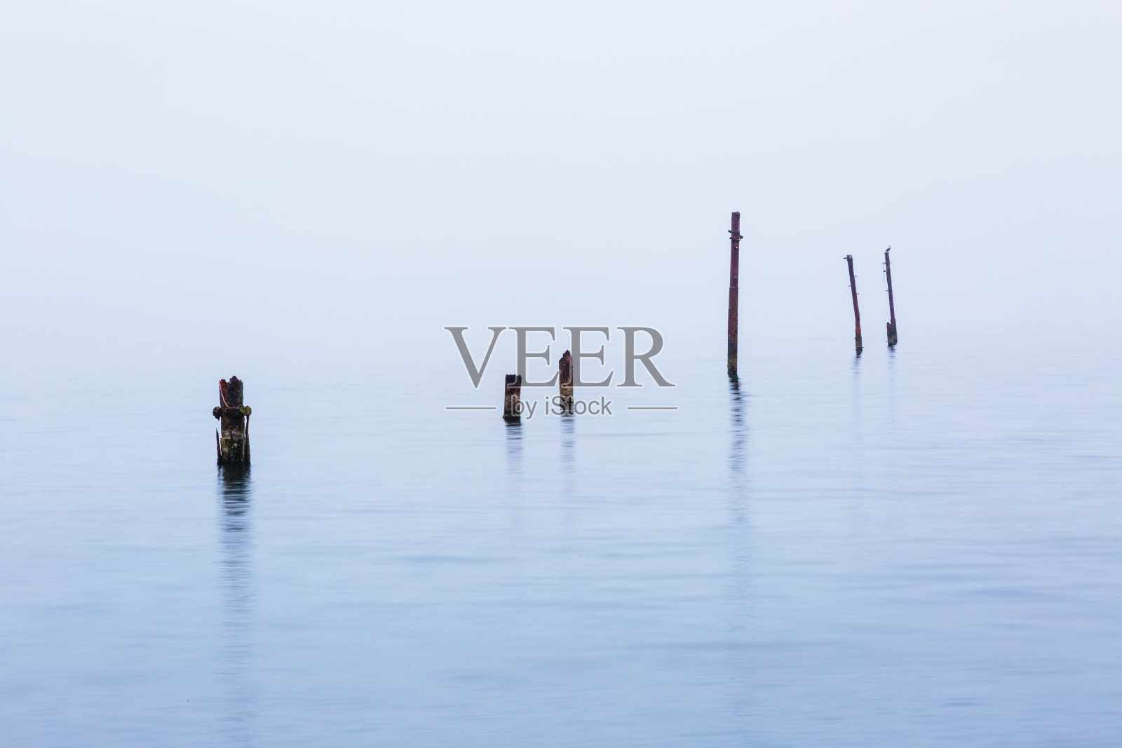 在恶劣的阴雨天气里,桥梁上被毁坏的旧桩被扔进海里照片摄影图片