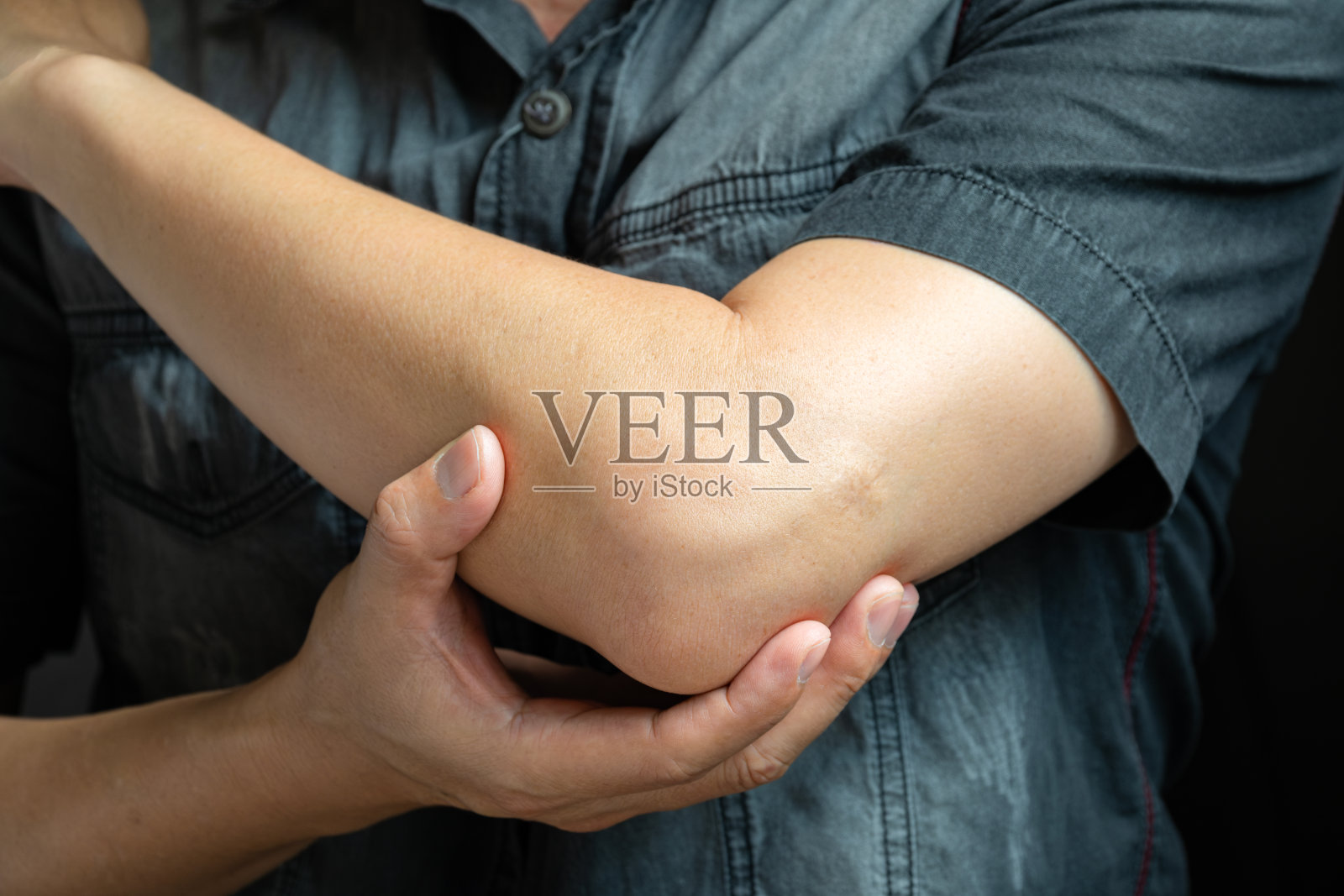 男人触摸肘部,肘部疼痛,他通过按摩缓解疼痛。健康与疗愈理念照片摄影图片