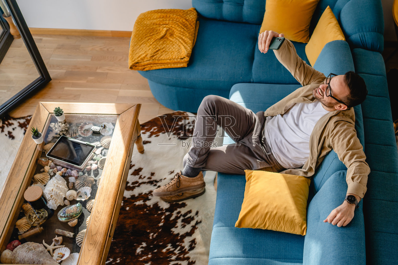 成年男子坐在客厅的沙发上,通过视频通话交谈照片摄影图片