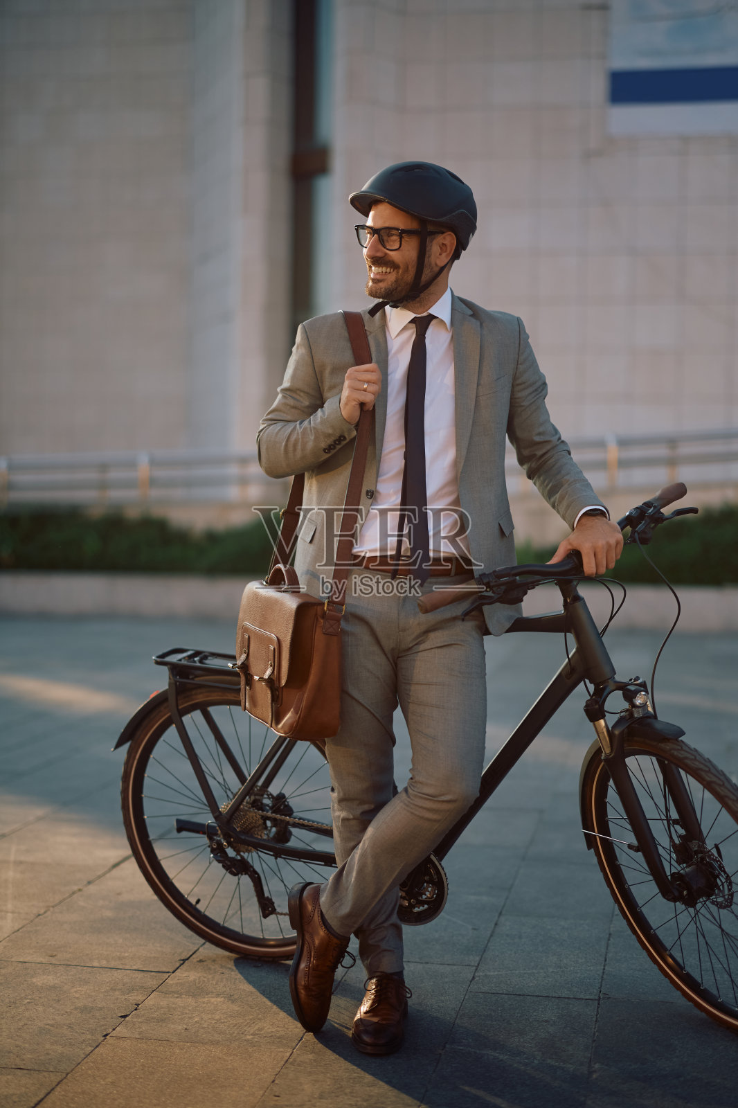 快乐的商人骑着自行车在街上望着别处。照片摄影图片