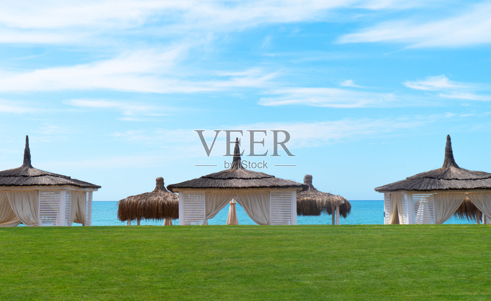 日落时白色的海滩树冠。豪华海滩度假胜地的豪华海滩帐篷。夏季海滩概念。水平房。暑假和假期照片摄影图片