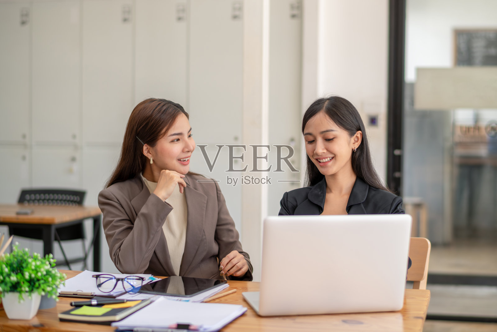 两个业务同事在笔记本电脑上与团队远程会议时交流想法。照片摄影图片