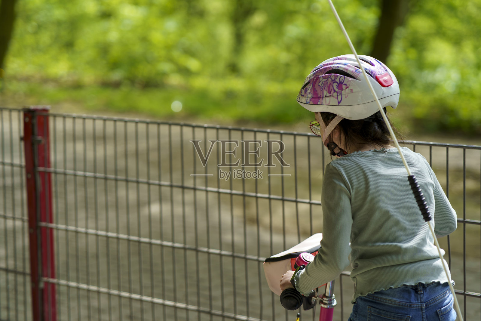 可爱悲伤的骑车小女孩戴着头盔坐在她的车上照片摄影图片