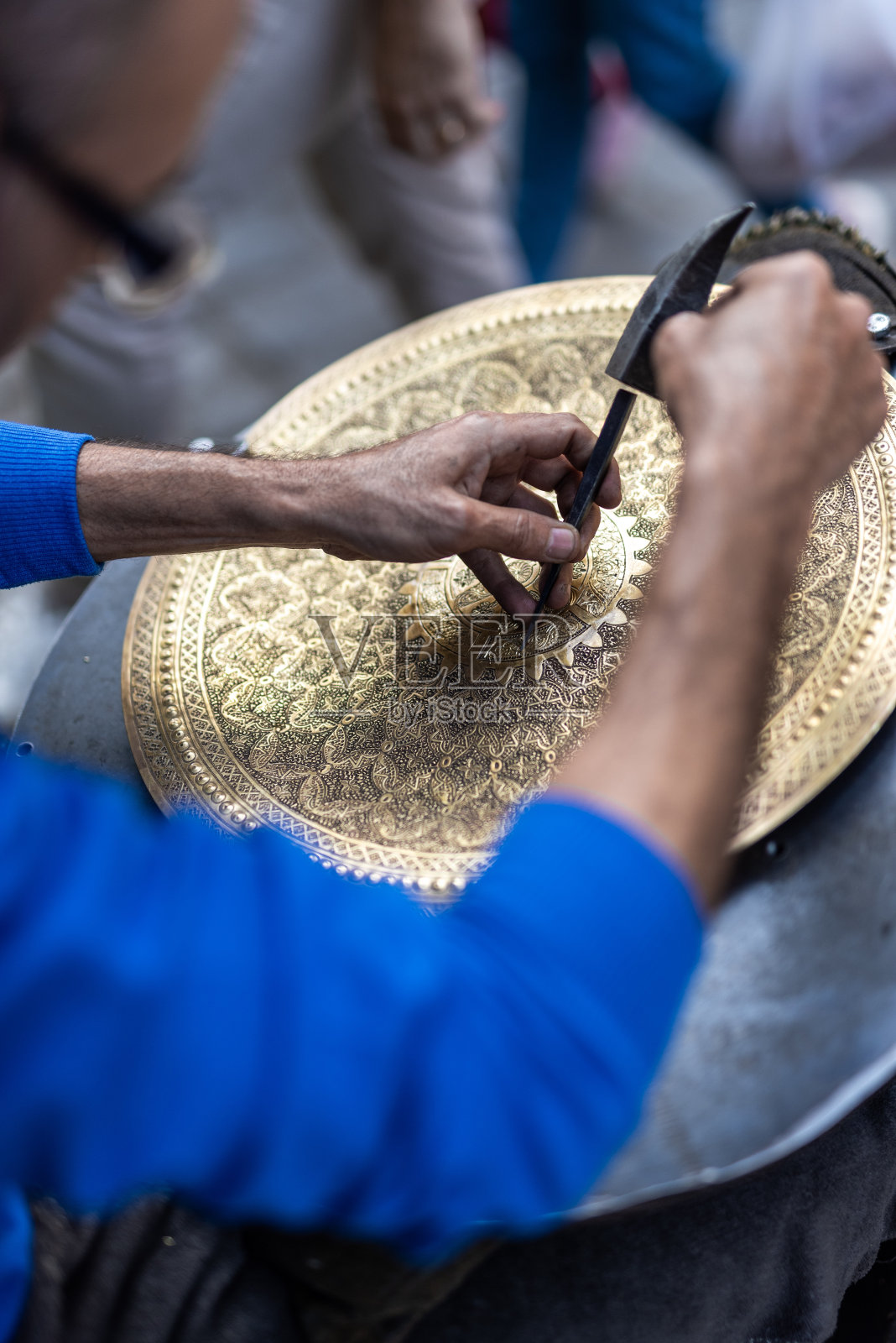 埃及男子在他的工作室里雕刻黄铜托盘照片摄影图片