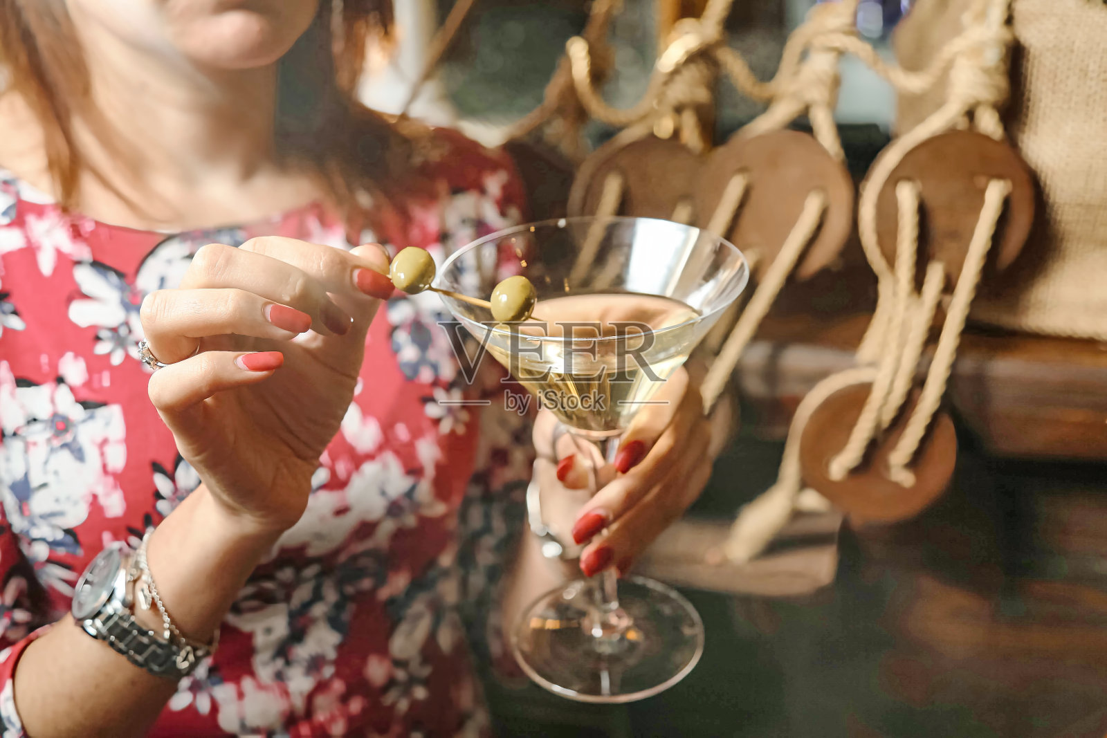 拿着马提尼杯的女人洒了橄榄照片摄影图片