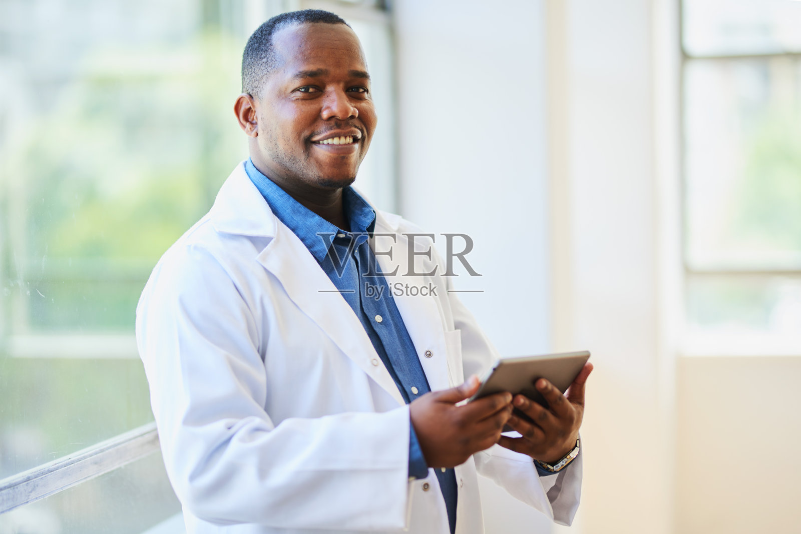 现代医院环境中,自信的黑人医生面带微笑,手持药片照片摄影图片