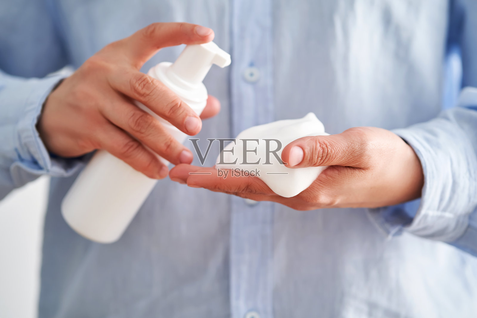 穿着蓝色衬衫的手拿着美味的面部泡沫,展示着它的质地。照片摄影图片