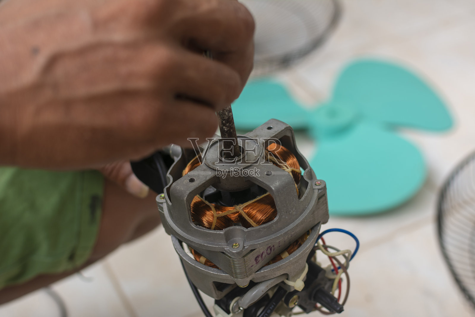 一个人检查转子轴是否有旋转问题。修理卡住的杆。清洁和修理电风扇。照片摄影图片