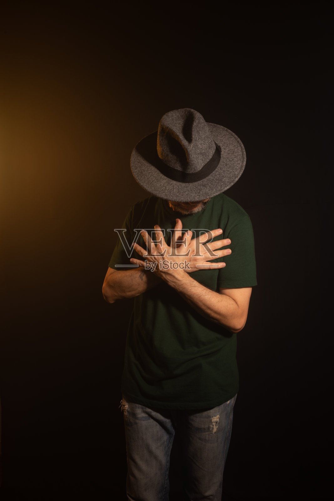 戴着帽子的神秘男子站着摆姿势拍照。工作室肖像。照片摄影图片