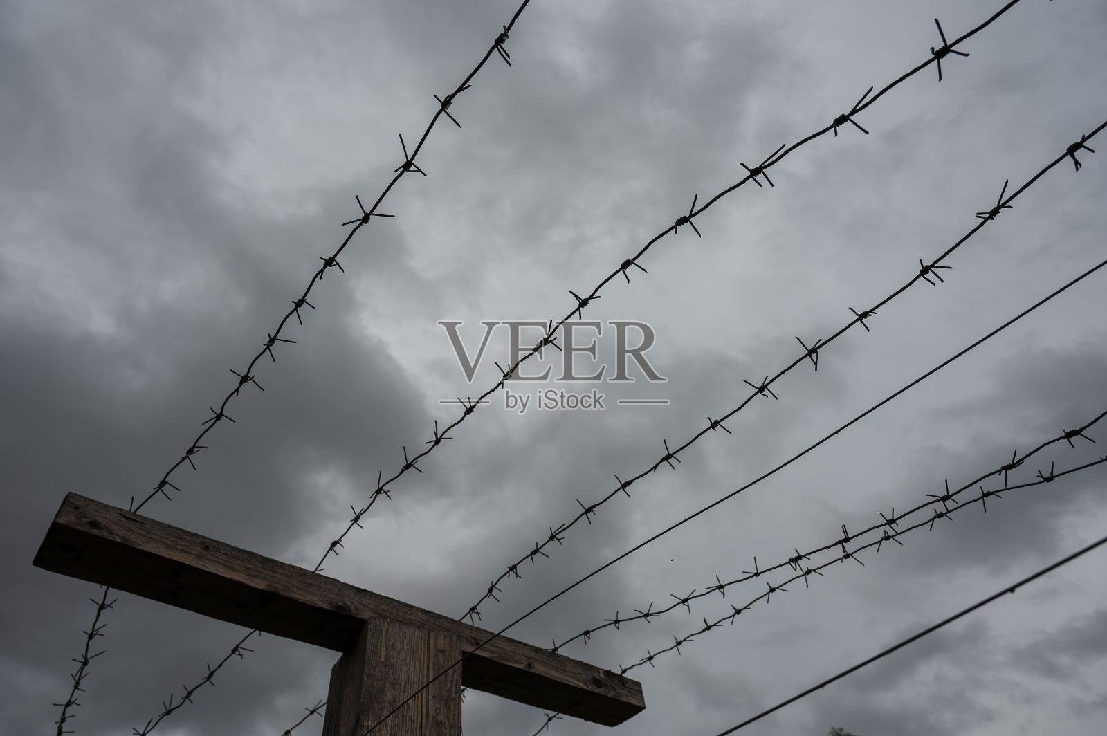 灰色云层背景上的铁丝网特写。照片摄影图片