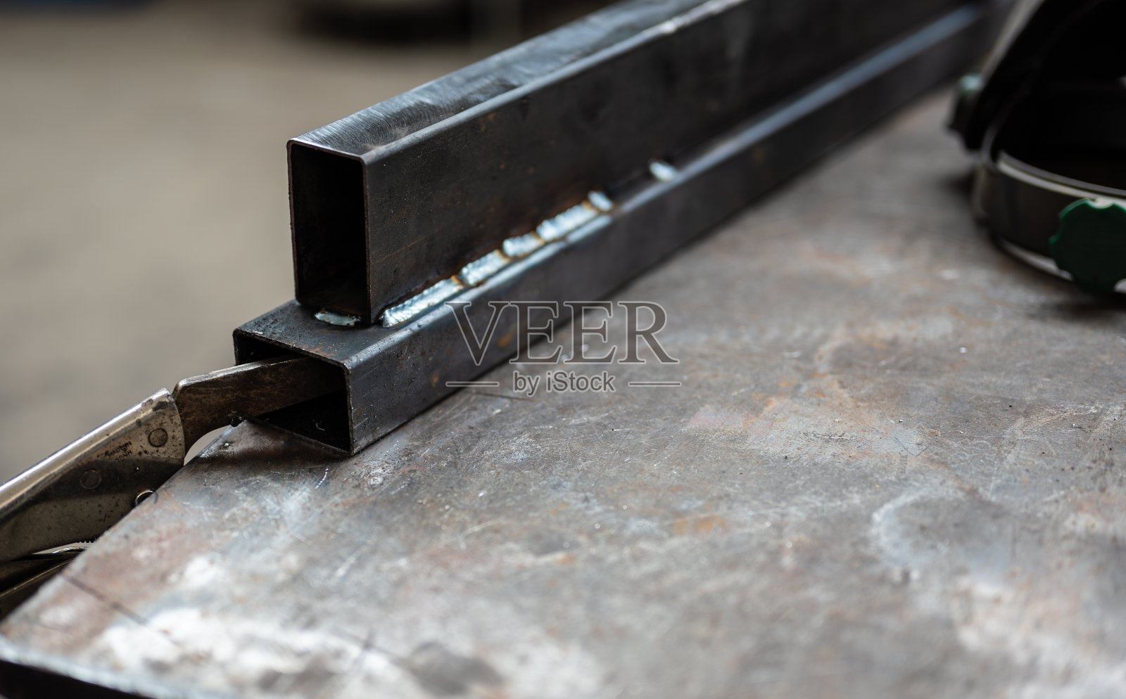 工作中的概念形象:在一个车间里,有选择地聚焦在两根金属棒的焊接点上。工作理念,金属工艺工作,修补,创意。照片摄影图片