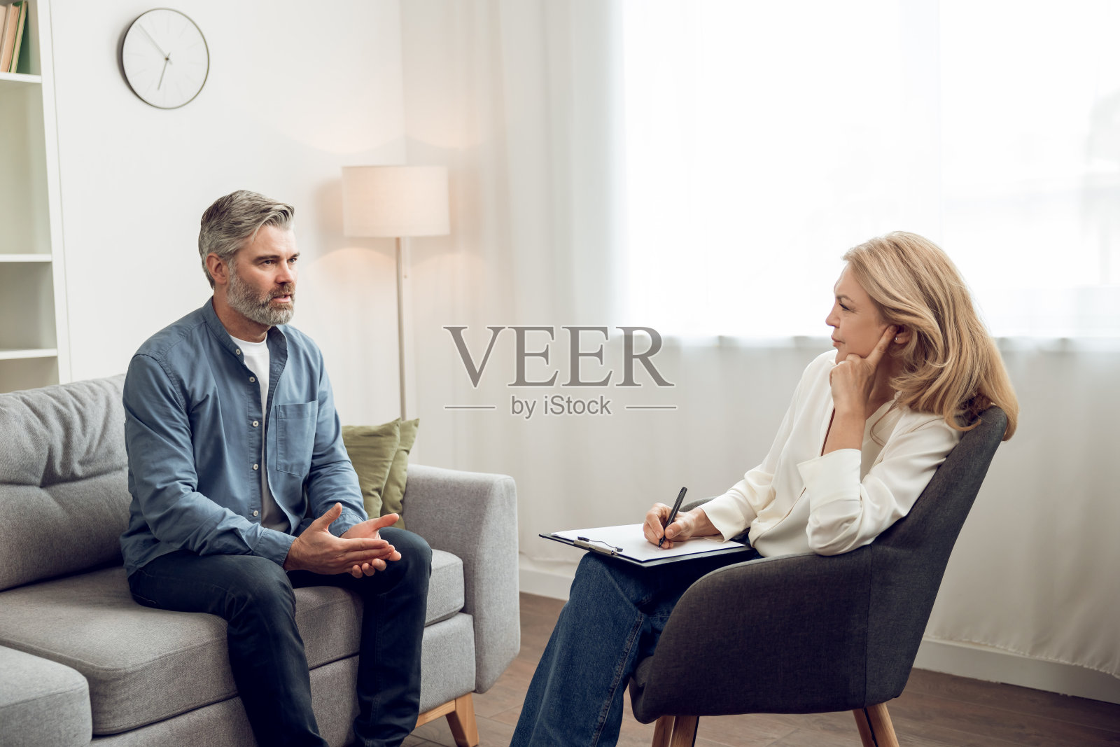 男人坐在咨询办公室的沙发上,向女心理医生抱怨他的烦恼照片摄影图片