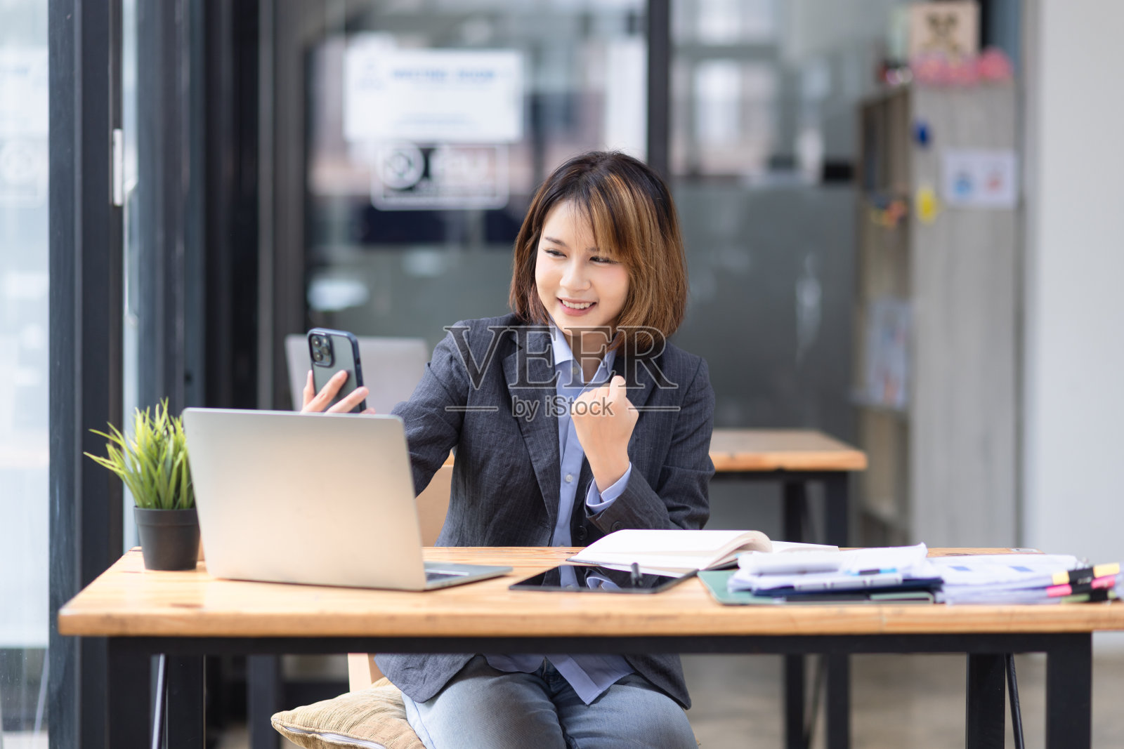 有魅力的亚洲女商人在办公室用智能手机和笔记本电脑工作。照片摄影图片