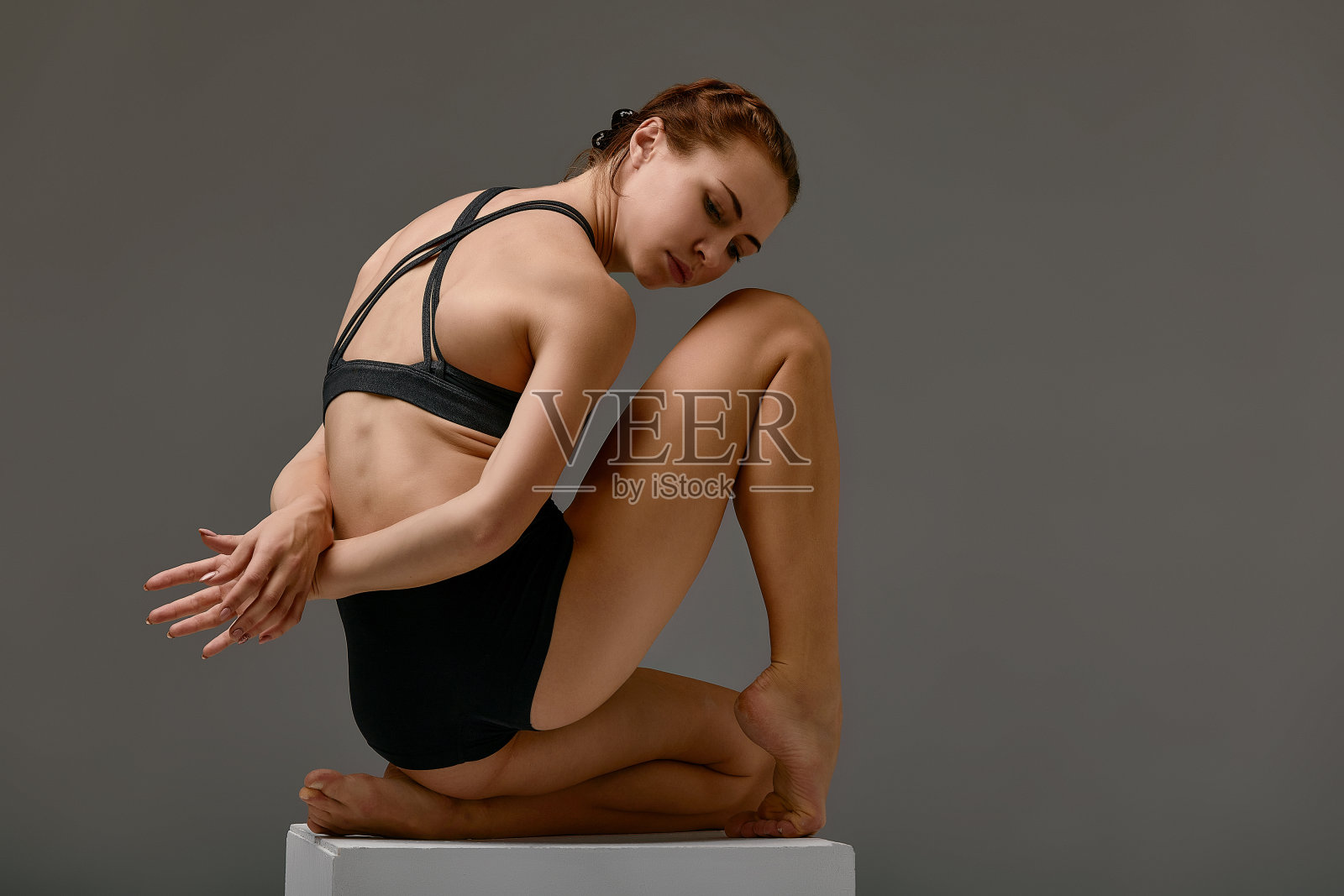 年轻的女孩专业体操运动员女子舞蹈艺术体操与白色立方体在工作室。照片摄影图片