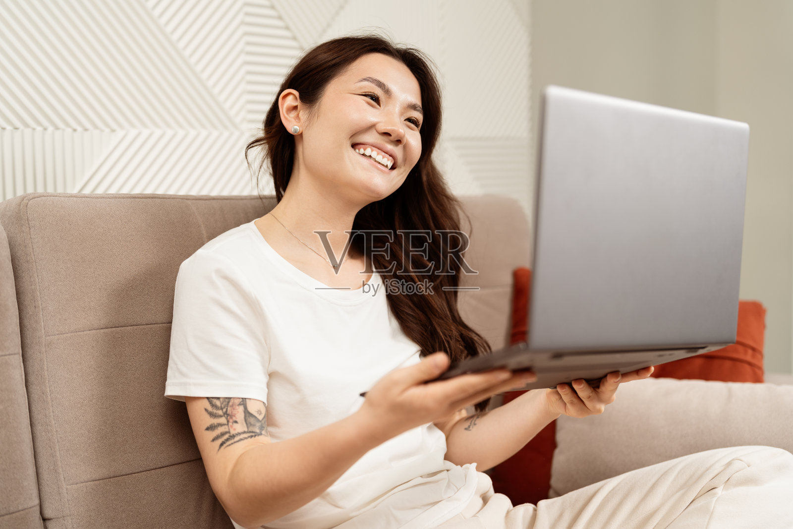 快乐的年轻女子在家里沙发上使用笔记本电脑照片摄影图片