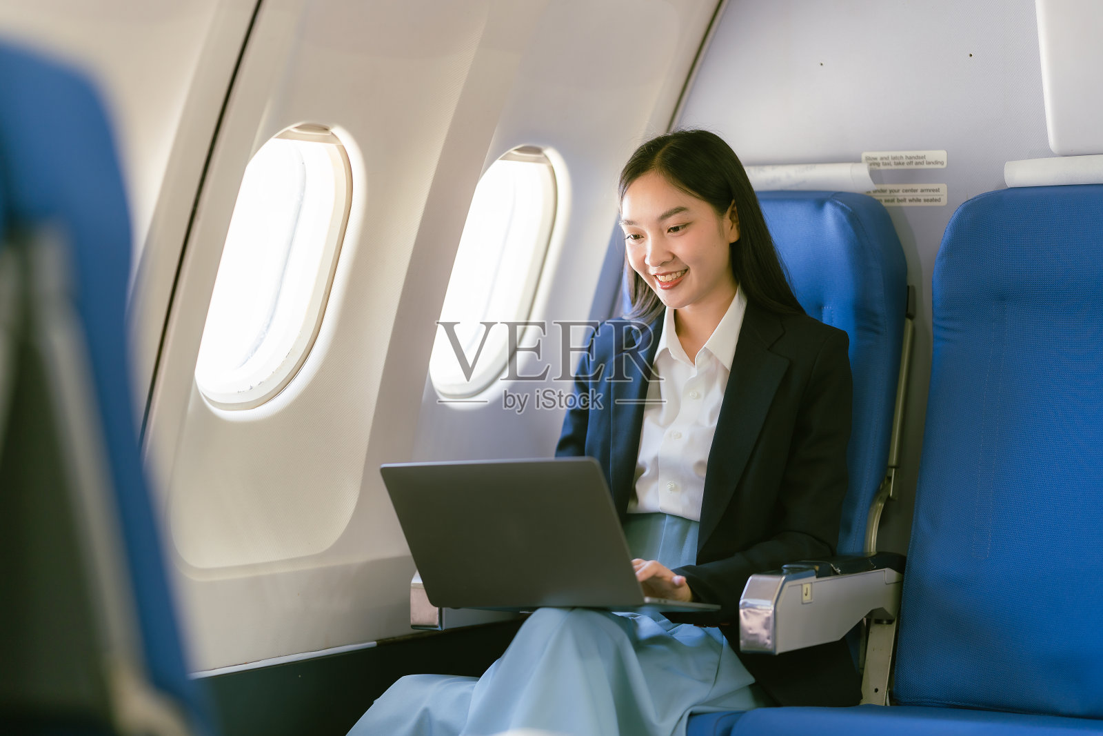 年轻的亚洲女性使用笔记本电脑,互联网,在线工作,在飞机上坐头等舱靠窗,旅行和商业概念照片摄影图片
