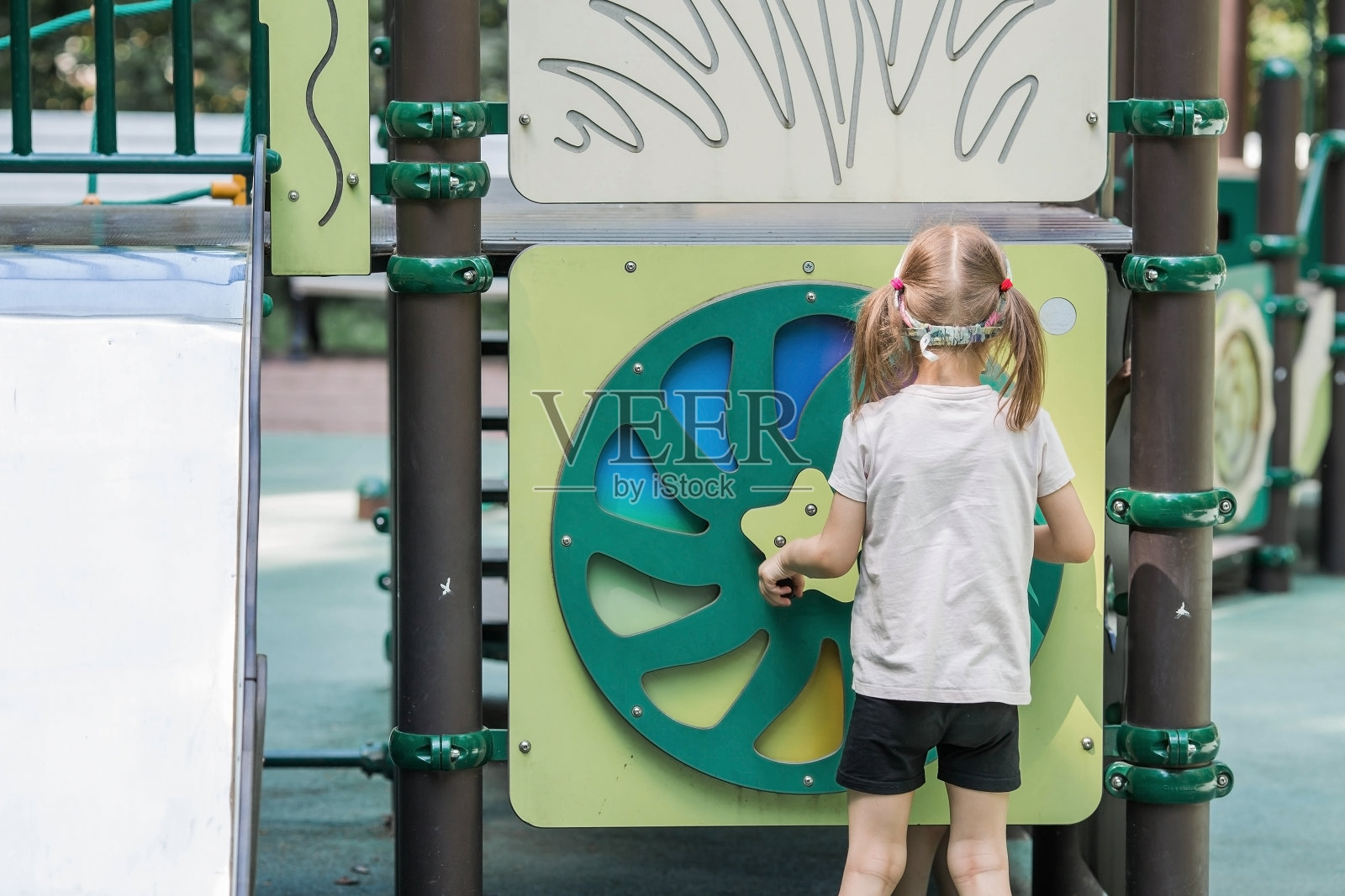 夏天,一个小女孩在操场上散步。在一个阳光明媚的春日,一个孩子在外面玩得很开心。儿童和儿童发展。照片摄影图片