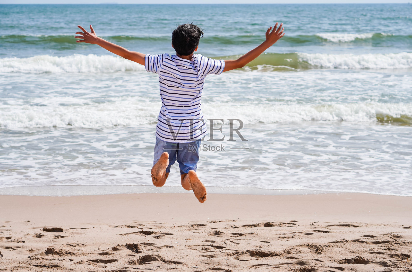 孩子在他的背上快乐地在大海前跳跃照片摄影图片