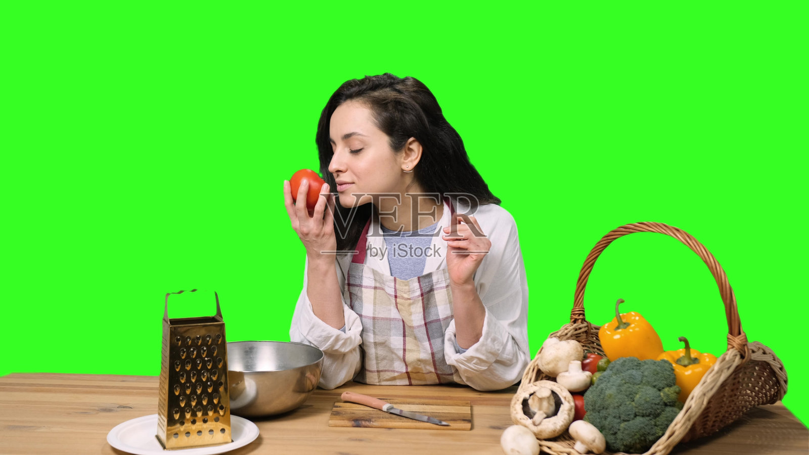 微笑的年轻女子闻着西红柿,开始按色度键烹饪照片摄影图片