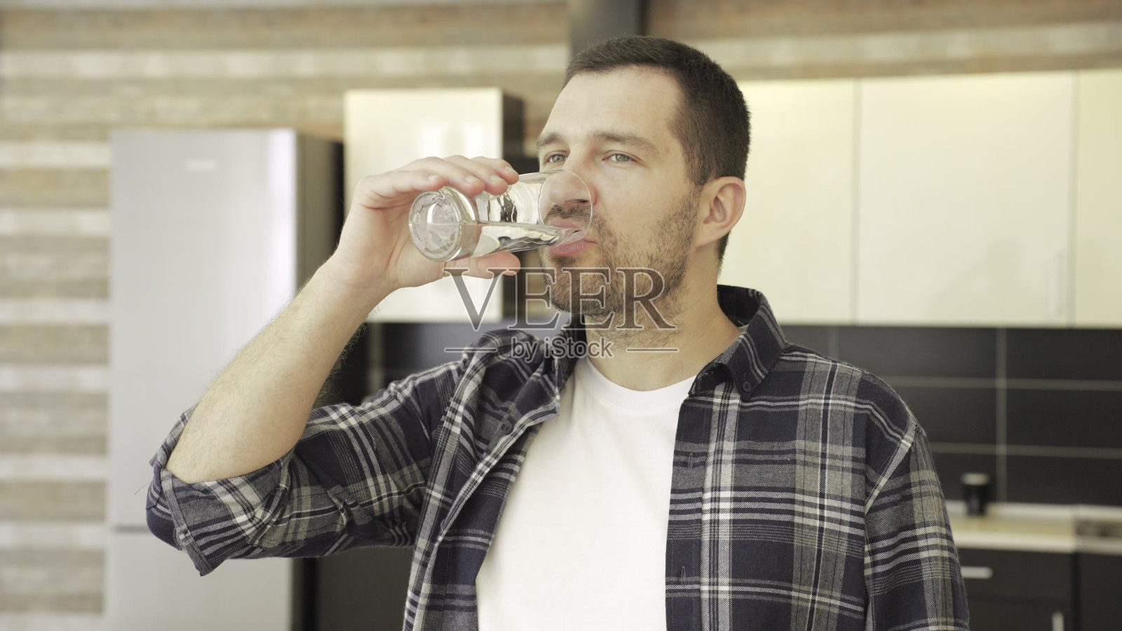 微笑的年轻人在家里的厨房边喝边享受照片摄影图片