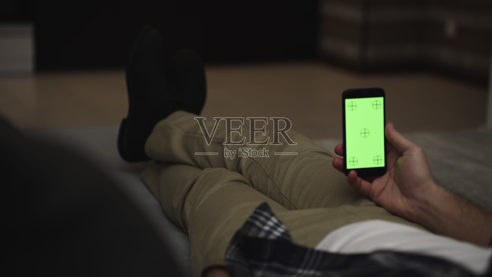 男人躺在沙发上使用带色度键绿屏的智能手机照片摄影图片