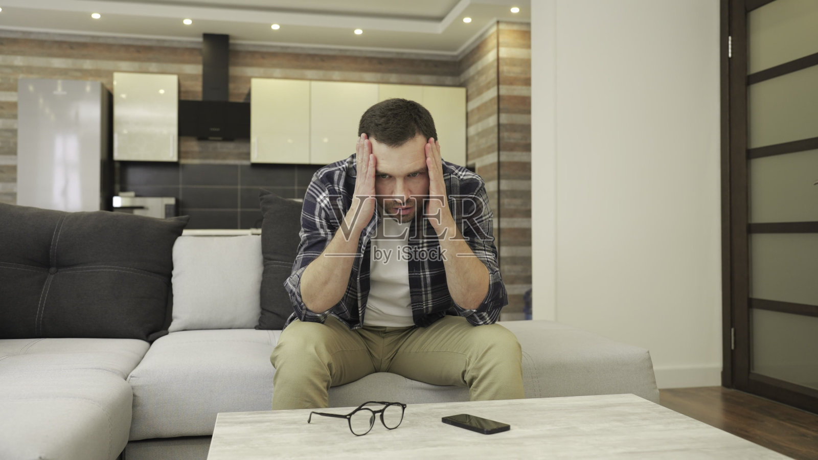 坐在沙发上,在家感到压力重重的年轻人照片摄影图片