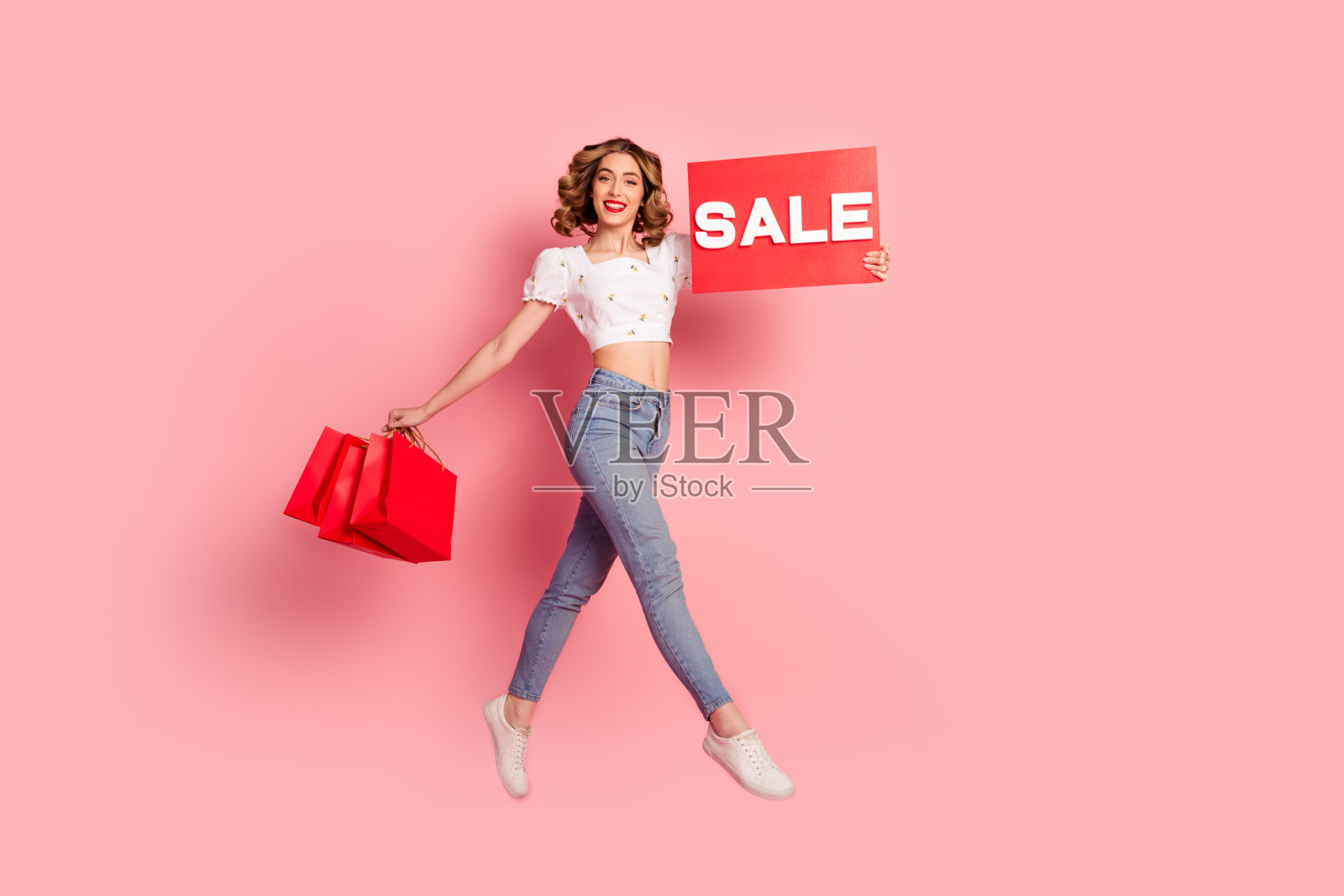 全尺寸照片可爱的年轻女子跳拿购物袋盘穿着时尚的白色服装发型孤立的粉红色背景照片摄影图片