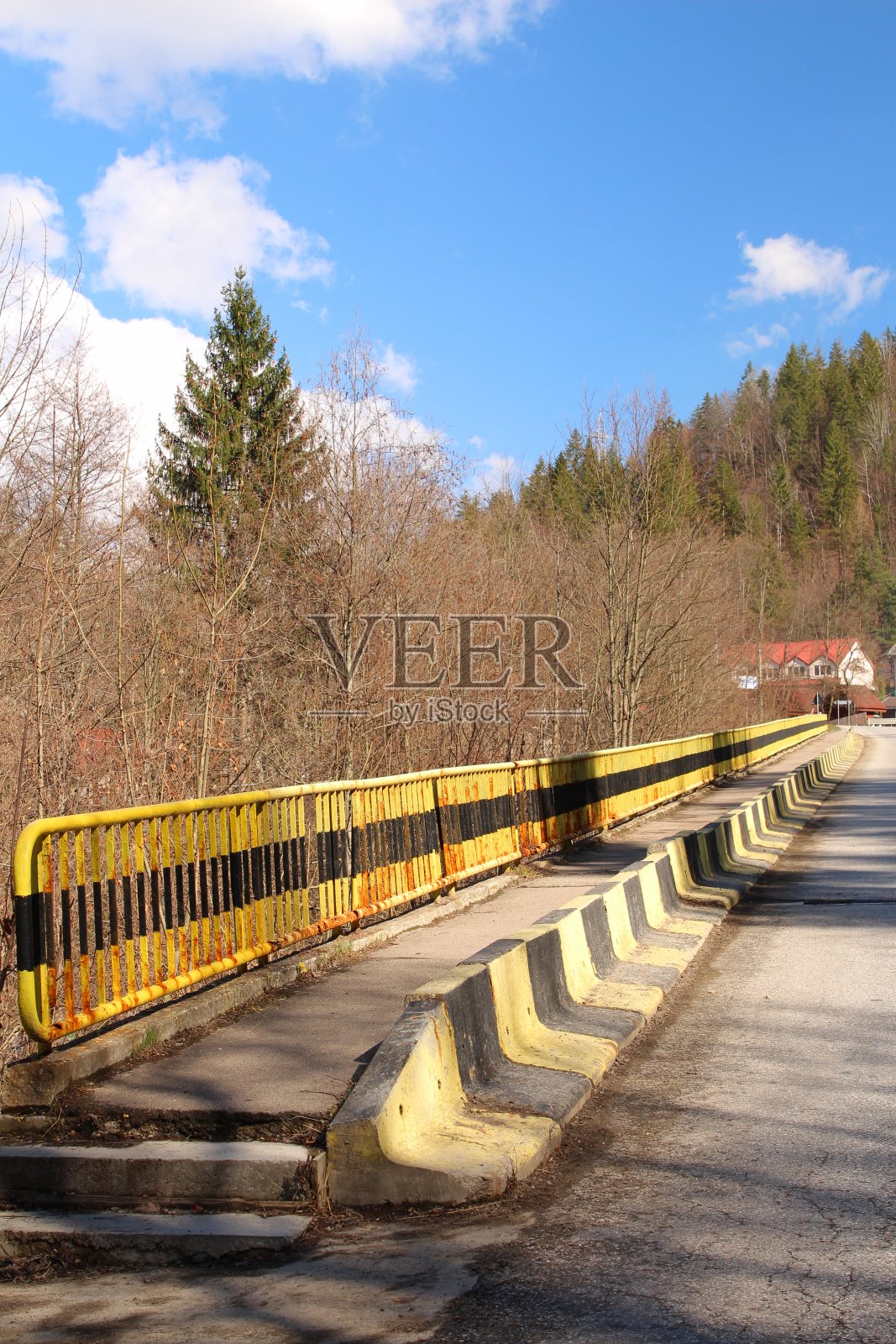 一条黄色的栏杆,背景是树木和一栋建筑照片摄影图片