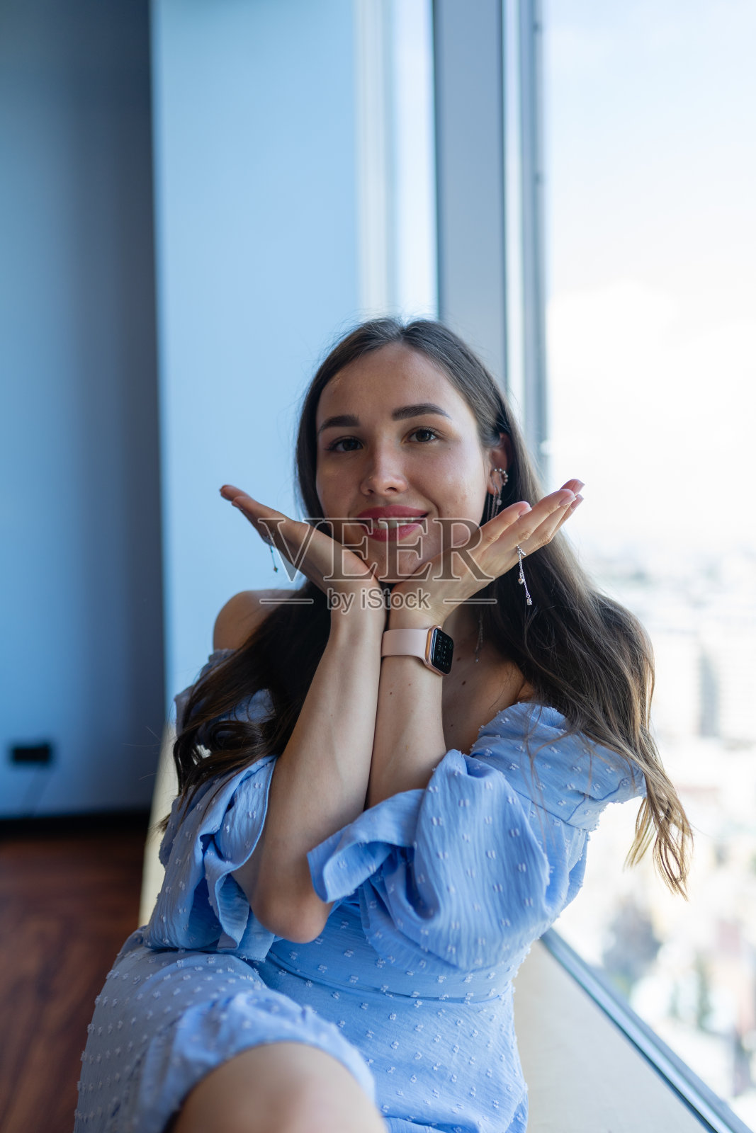 年轻女子微笑着摆姿势拍照,双手靠近脸照片摄影图片
