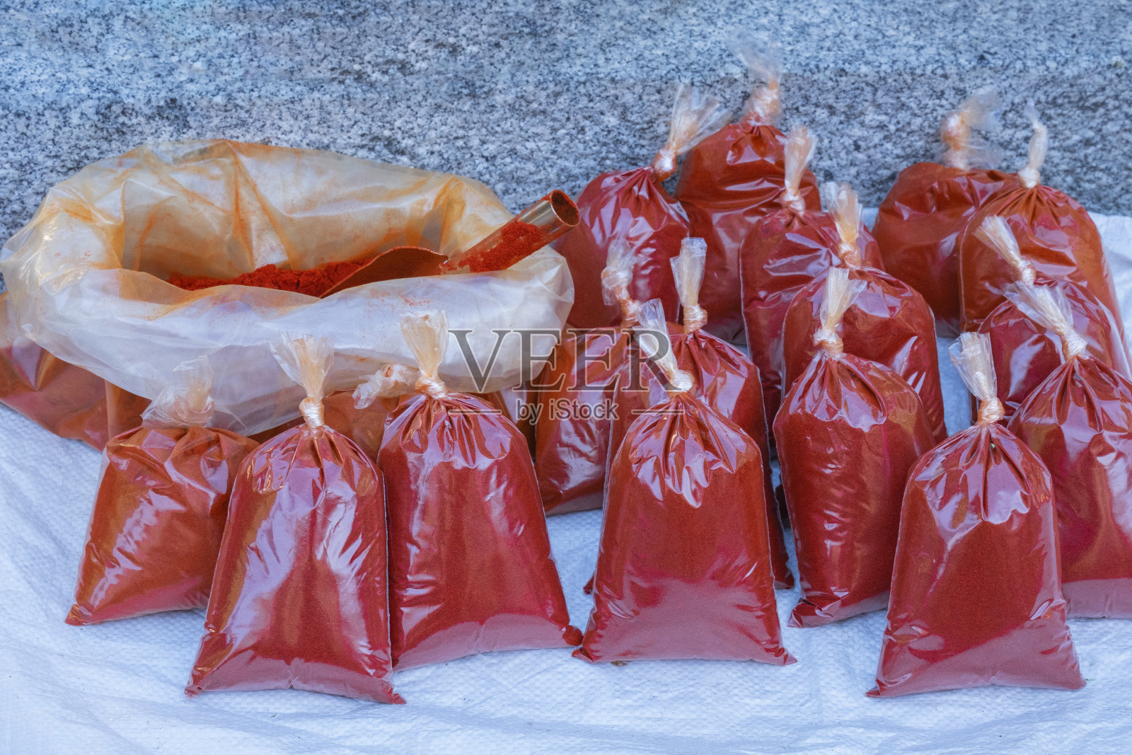 红色烟熏辣椒粉背景。透明塑料袋的La Vera辣椒在街头市场出售,真正的手工调味品。维拉辣椒被认证为受保护的原产地名称照片摄影图片
