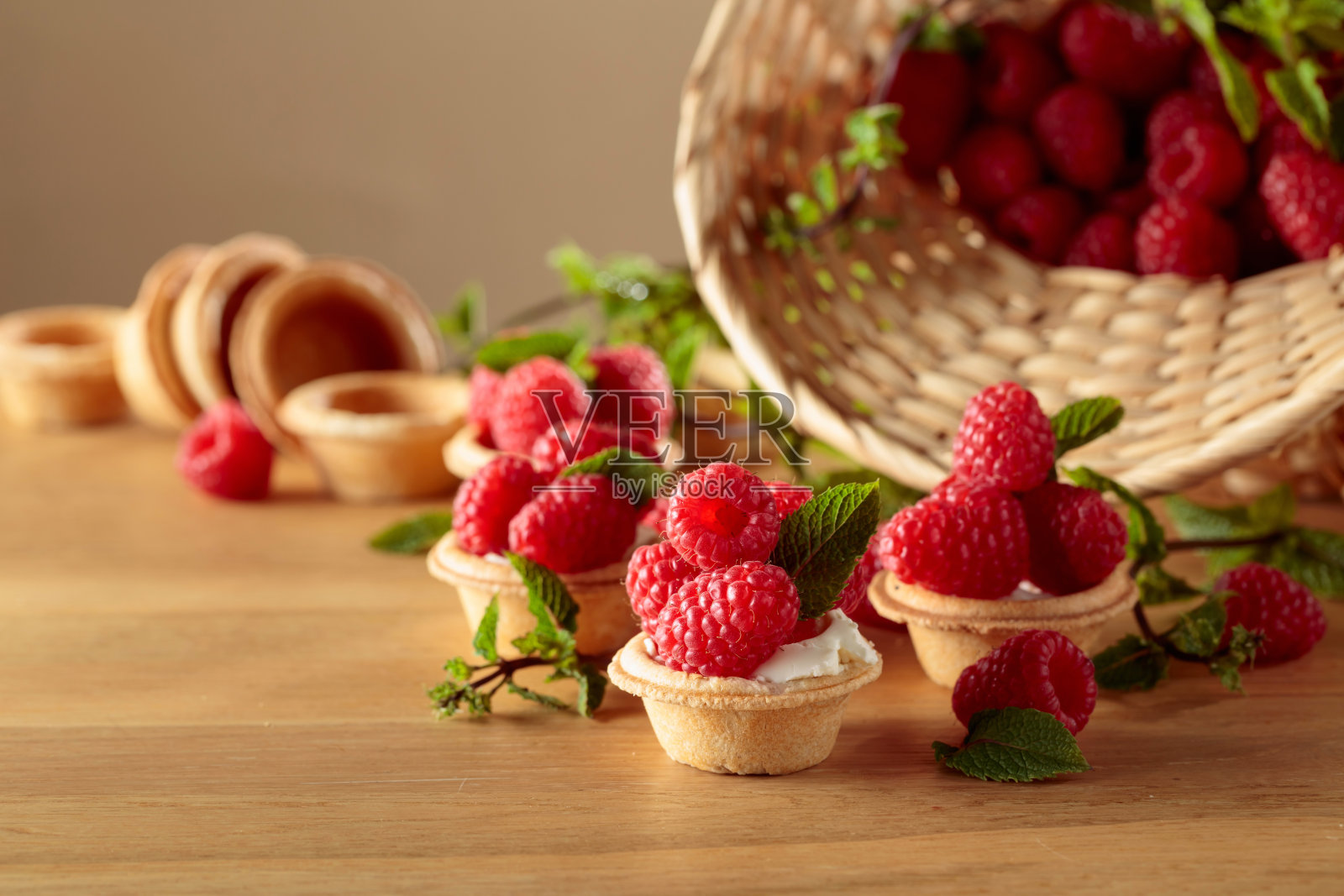 木桌上放着新鲜的覆盆子和薄荷馅饼。照片摄影图片